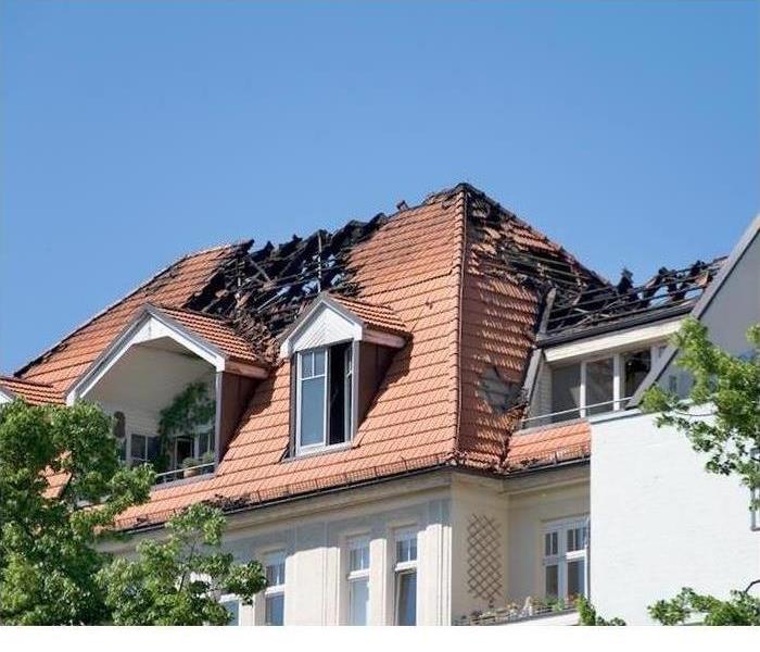 A house with a roof that has been damaged by fire is shown