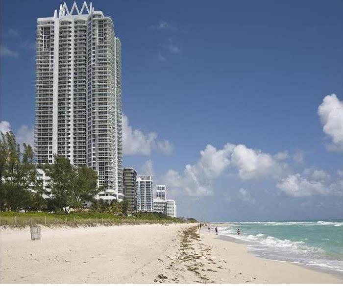 A tall condominium is shown on a beach